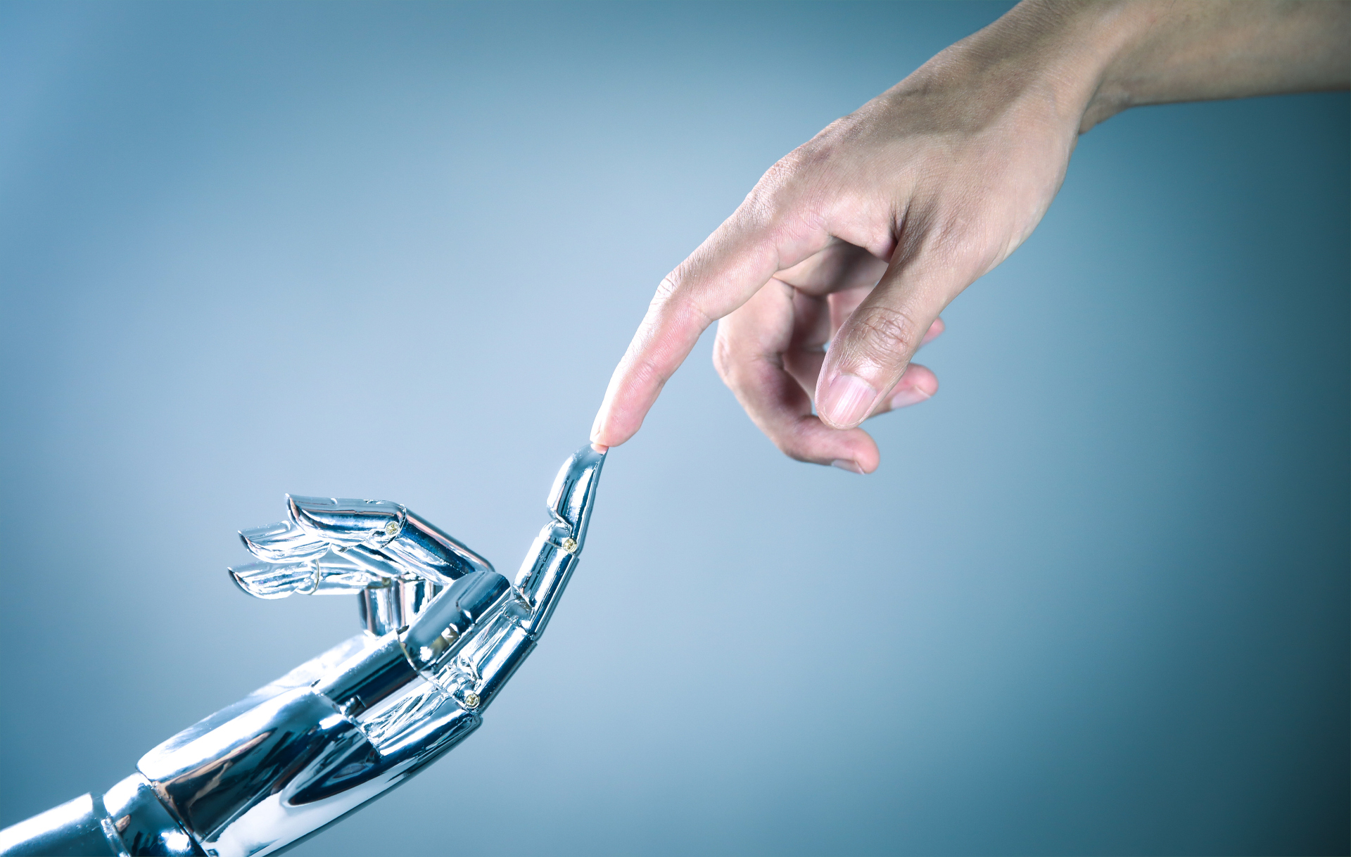 Eine Roboterhand und eine menschliche Hand berühren sich an den Zeigefingerspitzen