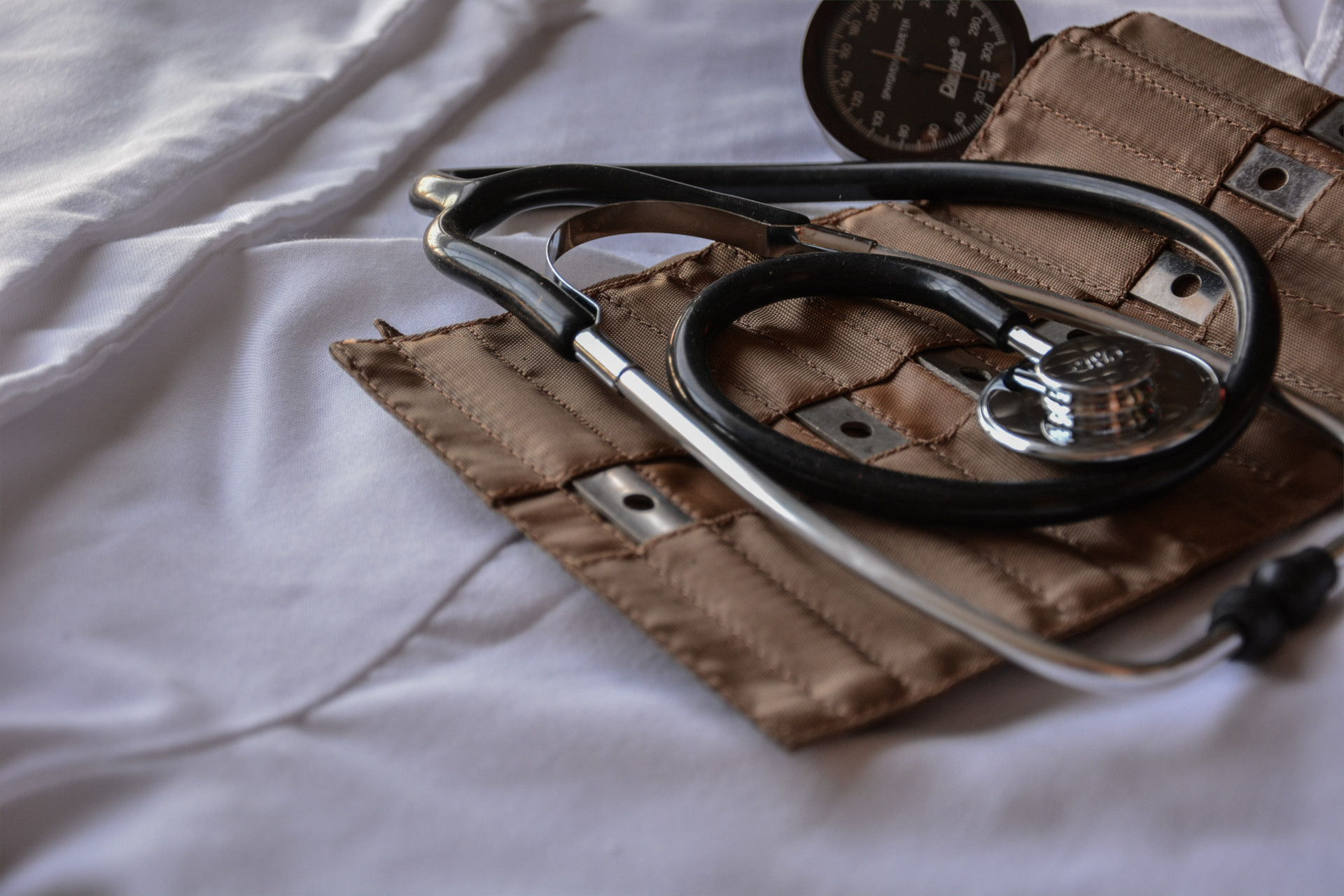 Ein Stethoskop auf einer weißen Decke und einer braunen Tasche